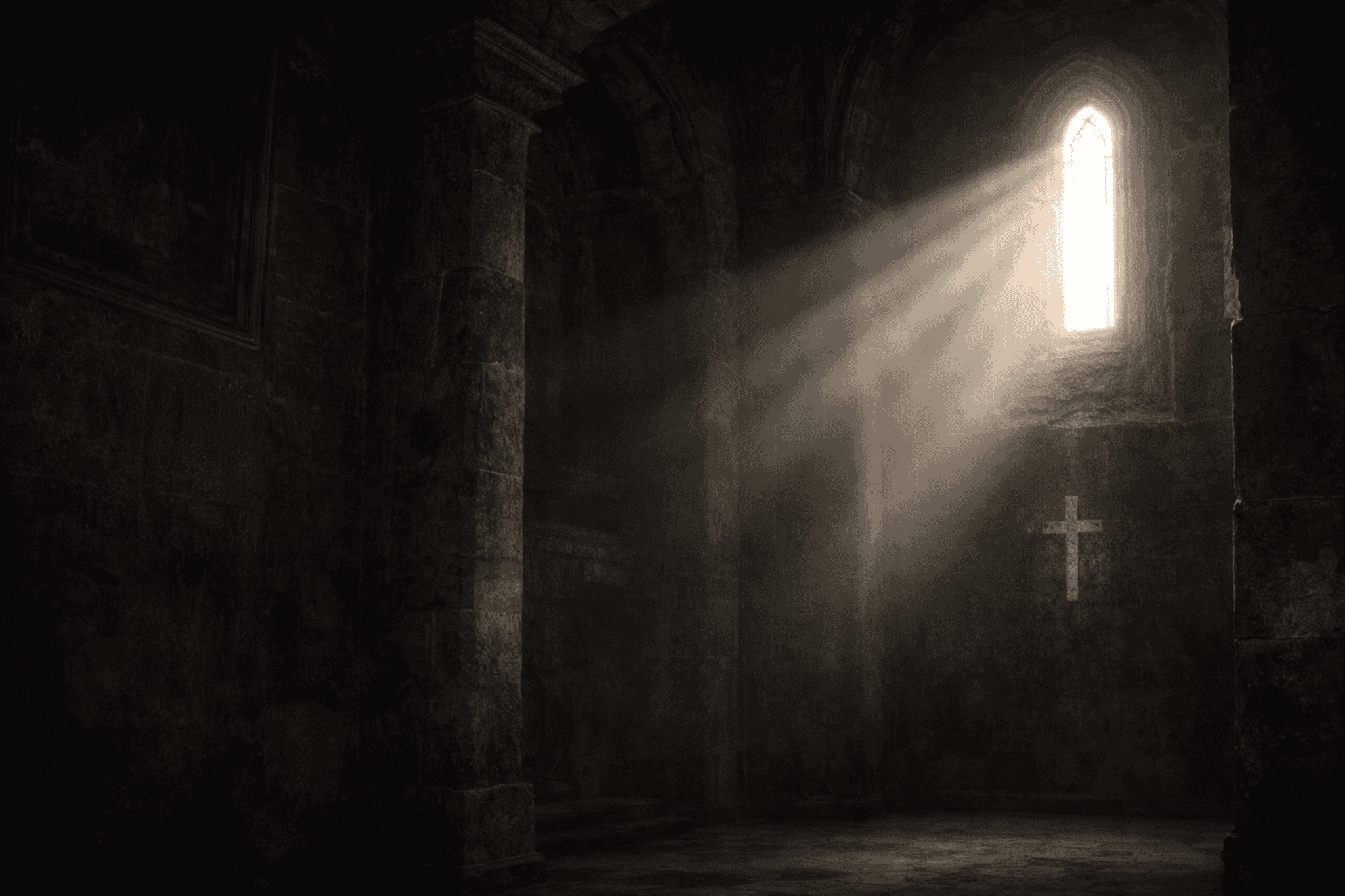 Old cathedral building with light rays shining through window and cross in middle